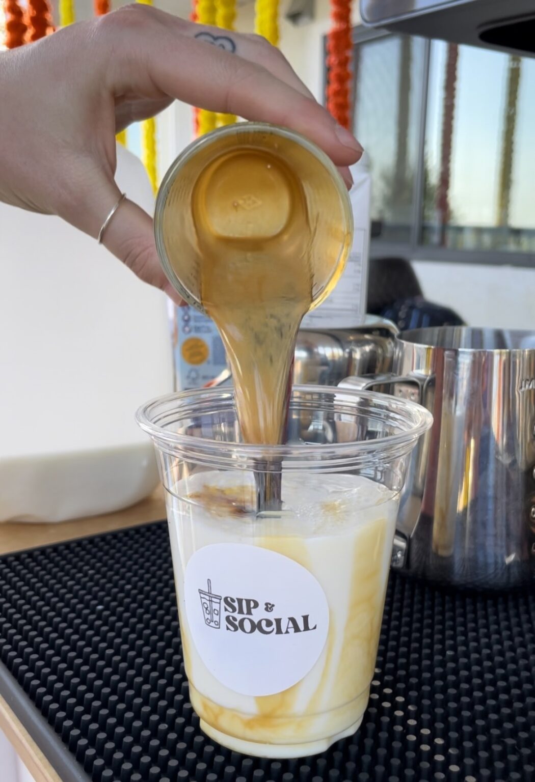 A Sip & Social barista pouring coffee into a cup