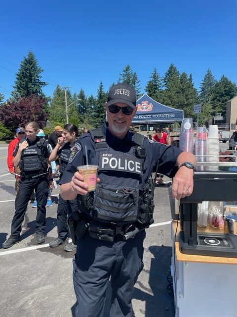 A police officer holding a coffee cup smiling